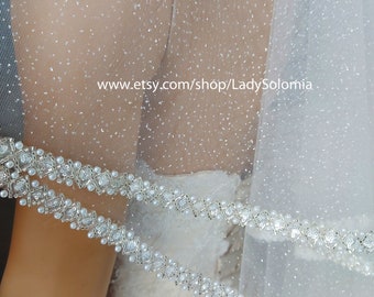 May include: A white bridal veil featuring a fine glitter finish and a decorative border of silver-toned metallic lattice work embedded with small white pearls and clear crystals. The text www.etsy.com/shop/LadySolomia is visible on the fabric.