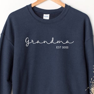 May include: A navy blue sweatshirt with the text "Grandma Est 2022" in white.
