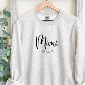 May include: A gray sweatshirt with the text "Mimi Est 2022" printed on the front.