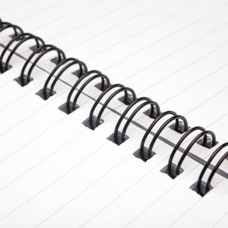 May include: Close-up of a black wire binding on a notebook. The binding is made of metal and has a series of loops that hold the pages together.