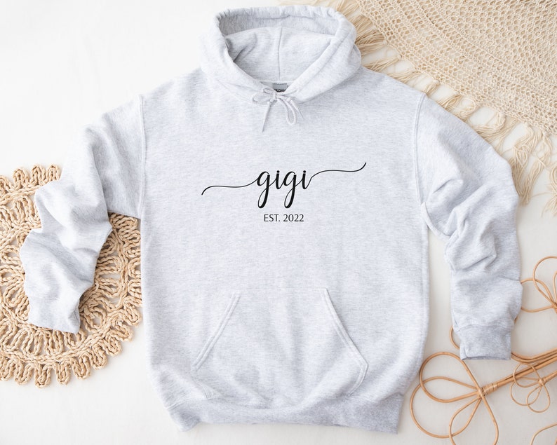 May include: Gray hooded sweatshirt with the text "gigi est. 2022" in black cursive lettering.
