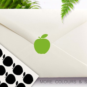 May include: An off-white envelope with a green apple graphic. A sheet of stickers with black apple silhouettes is in the lower left. The text "MORE COLOURS & SIZES" is at the bottom. The Confetti Barn logo is in the upper left.