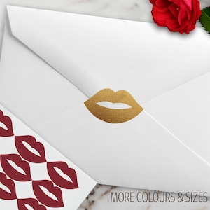 K&ouml;nnte beinhalten: Ein wei&szlig;er Umschlag mit einem goldglitzernden lippenf&ouml;rmigen Aufkleber auf der Klappe, begleitet von einem Bogen mit dunkelroten lippenf&ouml;rmigen Aufklebern. Der Text "CONFETTI BARN" und "MORE COLOURS & SIZES" ist auf dem Bild zu sehen.