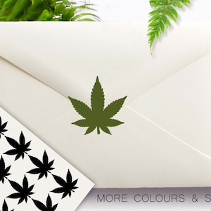 May include: An off-white envelope featuring a green cannabis leaf. A sheet of black cannabis leaf stickers is visible. The text "MORE COLOURS & SIZES" is at the bottom. The logo "Confetti Barn" is in the upper left corner.