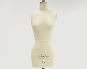 Puede incluir: Un maniquí de costura blanco con un soporte negro ajustable y ruedas. El maniquí está etiquetado como "Atelier Stand Professional Collapsible Shoulder 12".