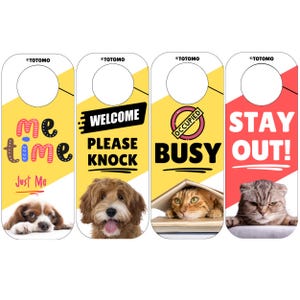 Pode incluir: Quatro cabides de porta com designs diferentes. Um diz "Me Time" com um cão, outro diz "Welcome Please Knock" com um cão, um terceiro diz "Occupied Busy" com um gato, e o último diz "Stay Out!" com um gato.