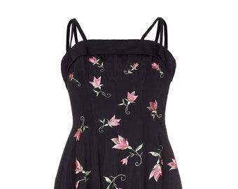 May include: A navy blue sleeveless dress with a fitted bodice and a full skirt. The dress is decorated with embroidered pink and green flowers.