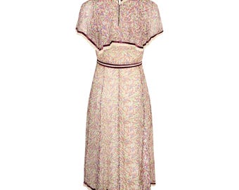 May include: A cream-colored dress with a floral pattern in shades of purple, green, and red. The dress features short sleeves, a fitted waist, and a midi-length skirt. It has a decorative trim around the neckline, waist, and hemline, adding a touch of elegance.