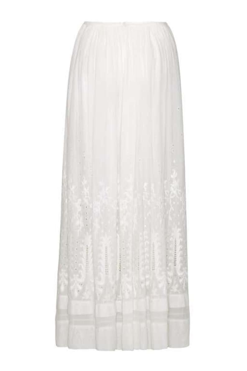 May include: A white maxi skirt with delicate embroidered floral details. The skirt has a flowy silhouette and a tiered ruffle hem.