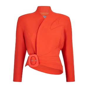 May include: A vibrant orange jacket with a unique design. The jacket features a wrap-style front, long sleeves, and a distinctive buckle closure at the waist. The tailored silhouette includes decorative stitching and a structured collar, creating a bold and stylish look.