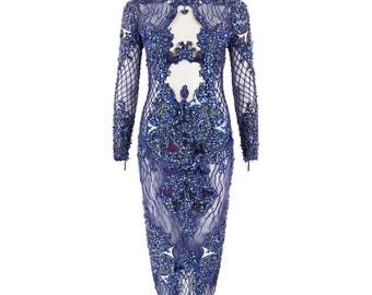 May include: A long-sleeved, knee-length dress in shades of blue, adorned with intricate beadwork and a sheer overlay. The dress features a keyhole cutout at the chest and a form-fitting silhouette, creating a glamorous and elegant look.