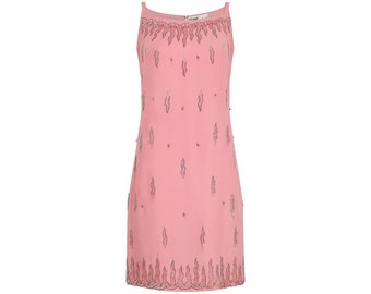 May include: A sleeveless pink mini dress featuring a square neckline and thin shoulder straps. The garment is decorated with vertical flame-like patterns and small circular accents in a dark metallic tone along the hem and neckline.