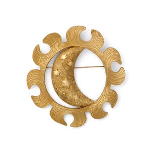 May include: A gold-toned brooch featuring a crescent moon with embedded stars, encircled by a decorative sunburst design. The brooch has a textured surface and a pin closure on the back. A celestial-themed accessory.
