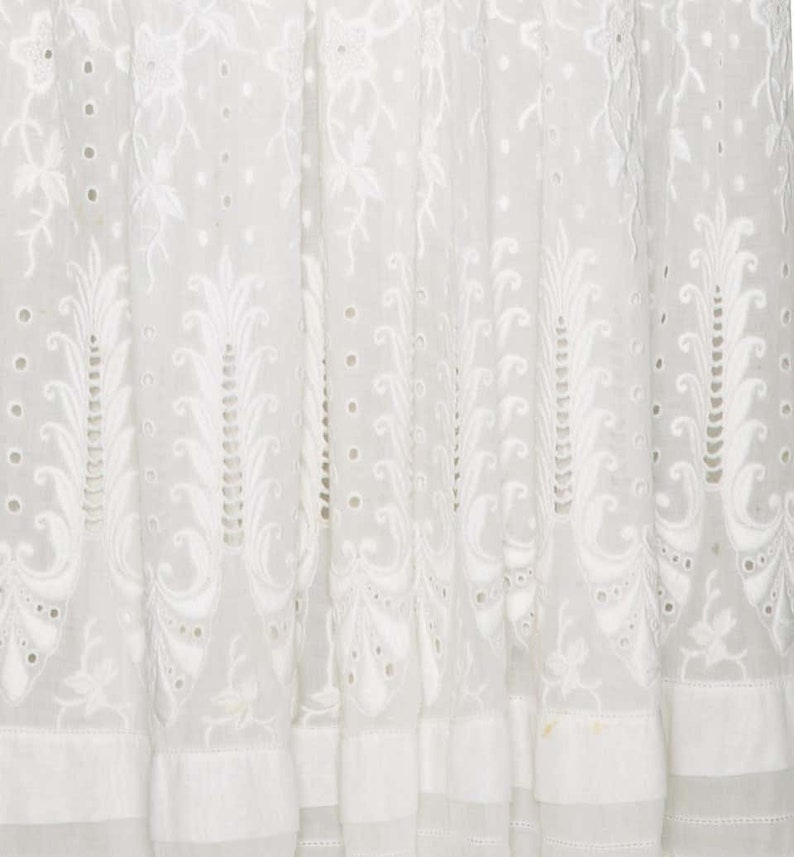 May include: White cotton fabric with a delicate embroidered pattern of leaves and flowers. The fabric has a sheer, airy quality and is perfect for a summer dress or blouse.