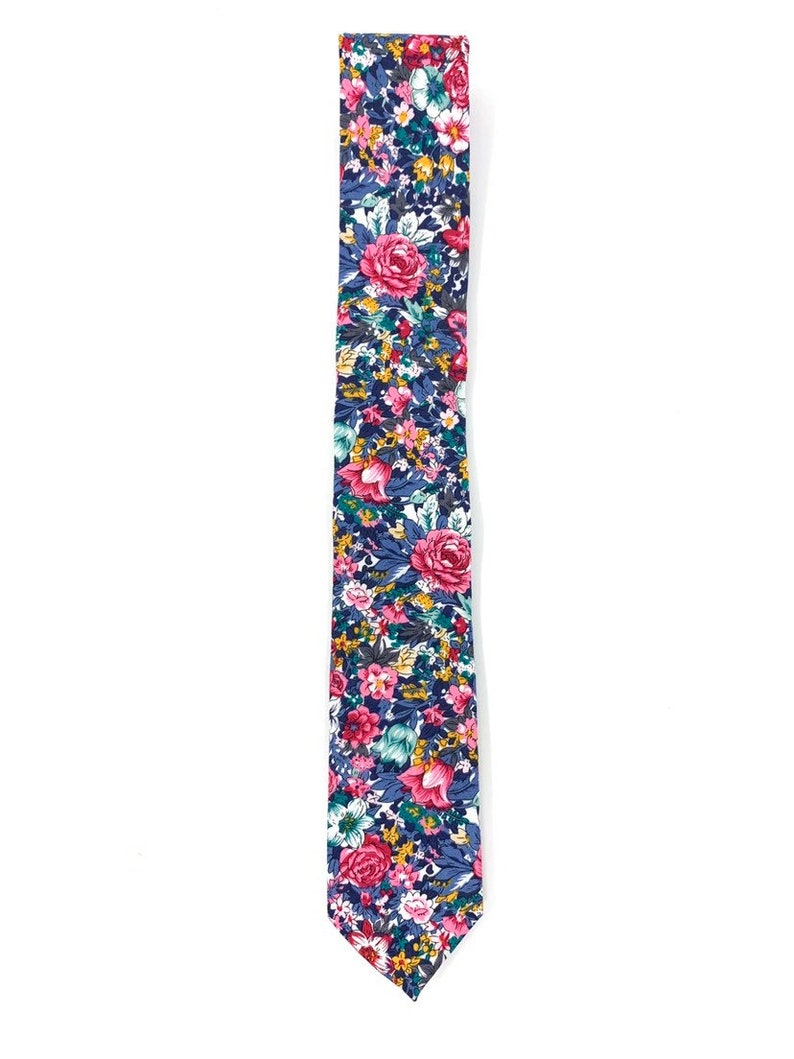 May include: A skinny tie with a floral pattern in shades of pink, blue, green, and yellow. The tie has a white background and features a variety of flowers, including roses and smaller blooms.