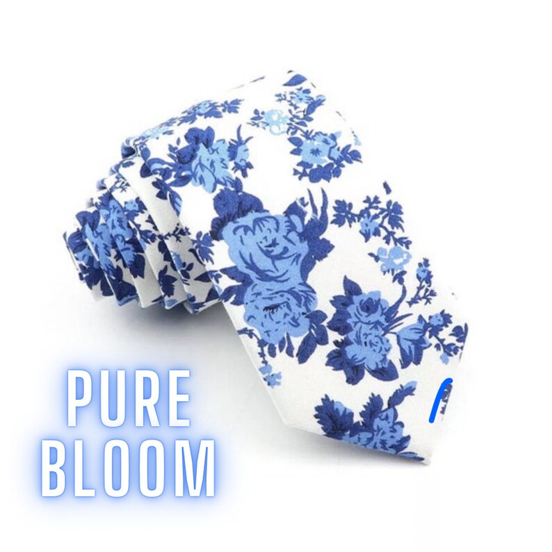 May include: White necktie with a blue floral pattern. The tie has a white background with blue roses and leaves. The text "PURE BLOOM" is printed on the tie.