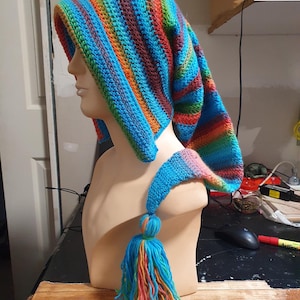 May include: A colourful crocheted hat with a long, striped tail and a tassel. The hat is blue, green, orange, red, and brown.