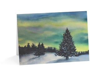 May include: A folded greeting card featuring a watercolor painting of a snowy landscape with dark evergreen trees under a vibrant sky of blended yellow, green, and blue hues, depicting a winter scene with a prominent pine tree in the foreground.
