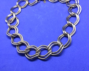 May include: A silver chain necklace with large, interlocking links. The links are twisted and have a polished finish.