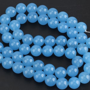 May include: A strand of light blue round gemstone beads. The beads are smooth and polished.