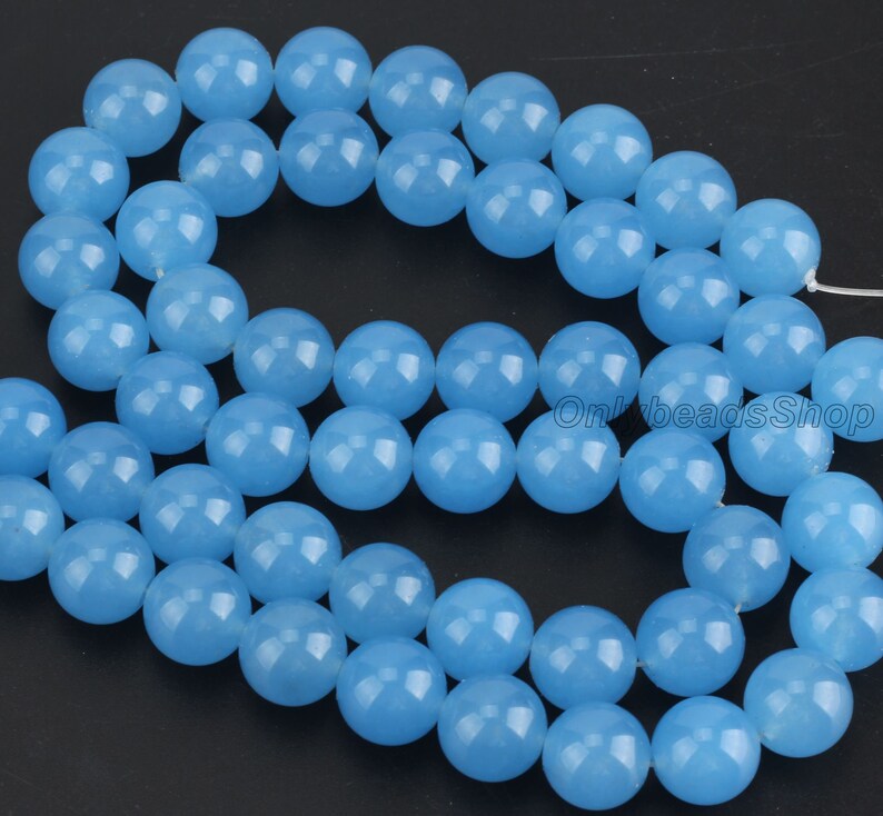 May include: A strand of light blue round gemstone beads. The beads are smooth and polished.