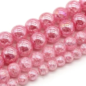 May include: A strand of pink, iridescent, round glass beads. The beads have a textured, sparkly finish.