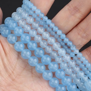 May include: A strand of light blue gemstone beads, with multiple strands of varying sizes, arranged in a graduated pattern. The beads are smooth and round, with a subtle shimmer.