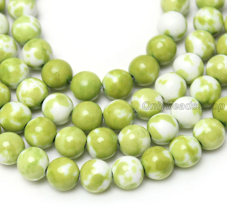May include: A strand of green and white jade beads. The beads are round and have a mottled pattern.