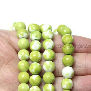 May include: A strand of green and white round beads. The beads have a mottled pattern of green and white.