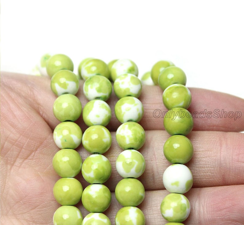 May include: A strand of green and white round beads. The beads have a mottled pattern of green and white.