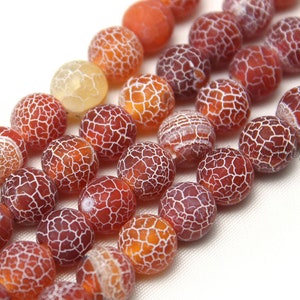Könnte beinhalten: Eine Strähne runder, roter, orangefarbener und gelber Achatperlen mit einem weißen Craquelé-Muster. Die Perlen haben einen Durchmesser von etwa 10 mm.