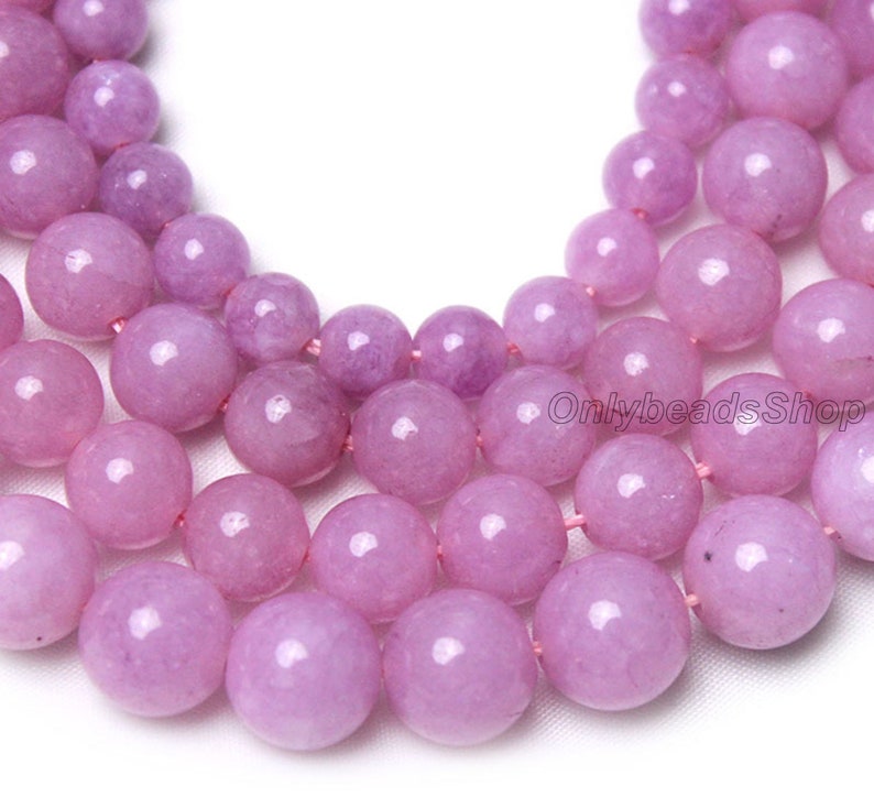 Puede incluir: Una hebra de cuentas redondas de piedras preciosas de color lavanda. Las cuentas son lisas y pulidas, con un ligero brillo. Las cuentas est&aacute;n enhebradas en un hilo delgado y transparente.