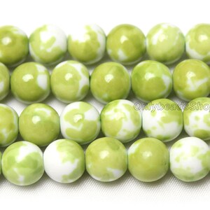 May include: A strand of green and white ceramic beads. The beads are round and have a marbled pattern.