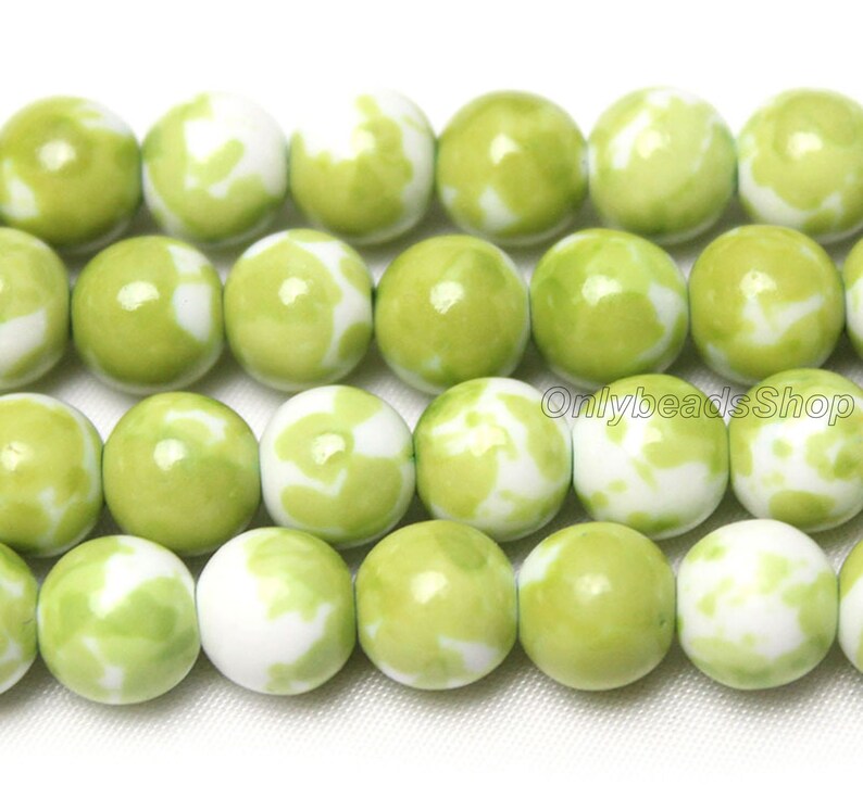 May include: A strand of green and white ceramic beads. The beads are round and have a marbled pattern.