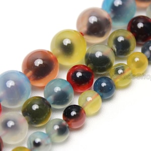May include: A strand of colourful agate beads with a variety of colours and patterns, including yellow, red, blue, and green. The beads are round and have a smooth, polished finish.
