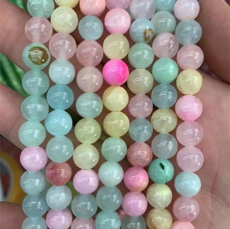 Puede incluir: Primer plano de un collar de cuentas de piedras preciosas de colores. Las cuentas son redondas y vienen en una variedad de colores pastel, incluyendo rosa, azul, amarillo y verde. Las cuentas est&aacute;n ensartadas, creando una pieza hermosa y llamativa.
