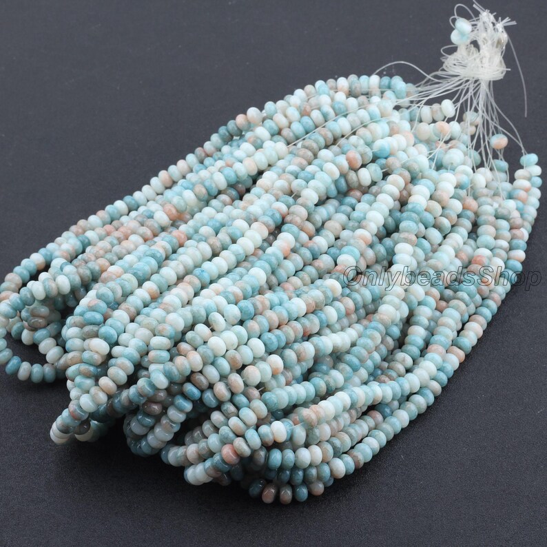 Pu&ograve; includere: Fili di piccole perline rotonde nei toni del blu, pesca e bianco. Le perline sono infilate insieme, creando un'esposizione strutturata e colorata. Le perline sono probabilmente destinate alla creazione di gioielli.