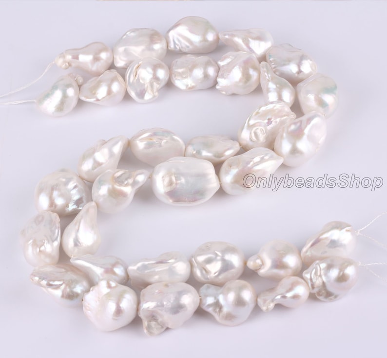 Peut inclure: Un brin de perles baroques blanches, chaque perle est de forme irr&eacute;guli&egrave;re et pr&eacute;sente un l&eacute;ger reflet iris&eacute;. Les perles sont enfil&eacute;es sur un fil blanc et sont pr&ecirc;tes &agrave; &ecirc;tre utilis&eacute;es pour la fabrication de bijoux.