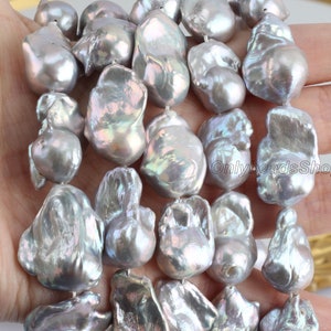 May include: A strand of large, irregular, baroque pearls. The pearls are a silvery grey colour with iridescent highlights.