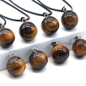 May include: Eight gold and brown tiger's eye stone ball pendants on black cords. Each pendant is approximately 1 inch in diameter.