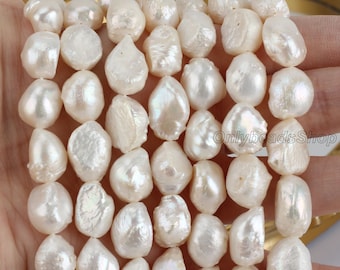 May include: A strand of white baroque freshwater pearls. The pearls are irregular in shape and have a smooth, lustrous finish.  The pearls are strung on a white thread and are approximately 10mm in size.
