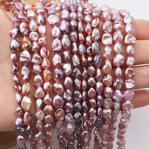 Può includere: Fili di perle d'acqua dolce dalla forma irregolare, nei toni del rosa, lavanda e pesca. Le perle hanno una forma naturale e organica e sono infilate, mostrando i loro colori e le loro trame uniche. Ideali per la creazione di gioielli.
