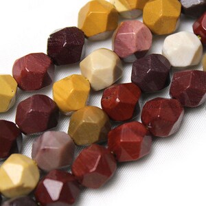 May include: A strand of faceted gemstone beads in shades of red, brown, yellow, and white. The beads are all faceted and have a unique, natural look.