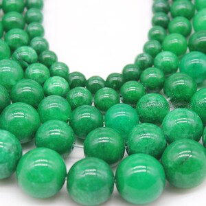 May include: A strand of round, green jade beads. The beads are smooth and polished, with a slight variation in color.