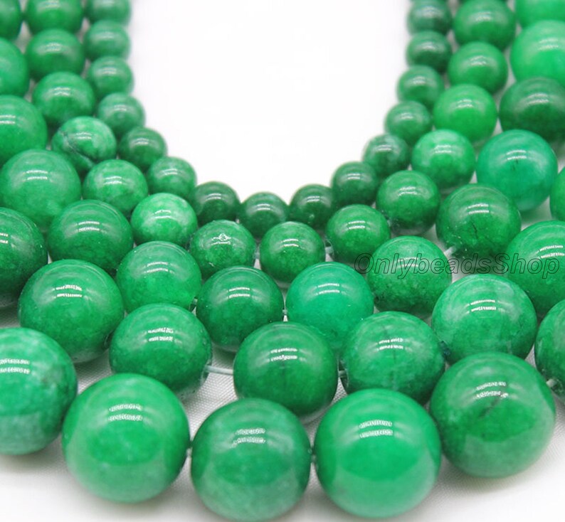 May include: A strand of round, green jade beads. The beads are smooth and polished, with a slight variation in color.
