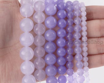 May include: Seven vertical strands of smooth, round beads in varying shades of purple and lavender. The beads are arranged by size, with the largest on the left and the smallest on the right. The text OnlybeadsShop is visible on the right side.