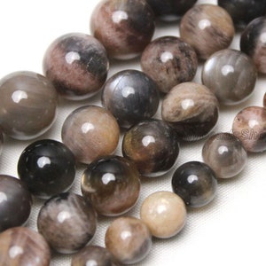 May include: A strand of round, iridescent gemstone beads in shades of brown, black, and grey. The beads have a smooth, polished finish and a subtle shimmer.