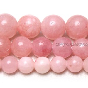 May include: A strand of pink rose quartz beads. The beads are round and smooth, and they have a natural, polished finish.