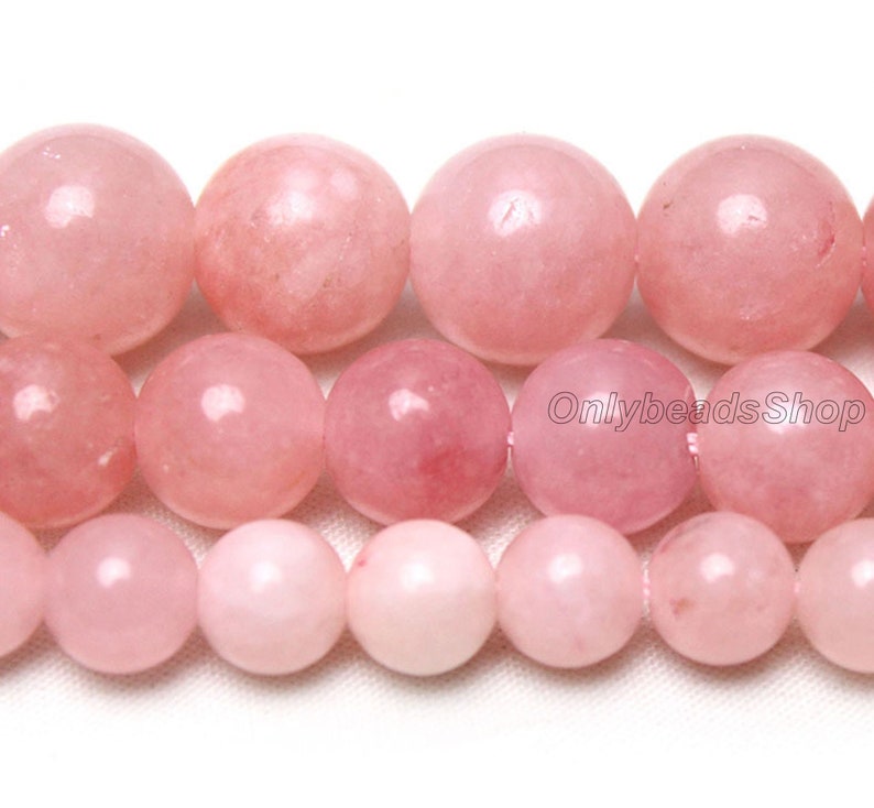 May include: A strand of pink rose quartz beads. The beads are round and smooth, and they have a natural, polished finish.