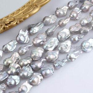 May include: A strand of grey baroque freshwater pearls. The pearls are irregular in shape and have a slightly iridescent sheen.